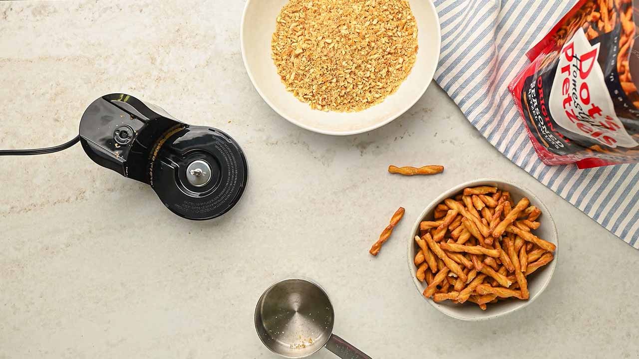 pouring the crushed dots pretzels pieces into a small bowl