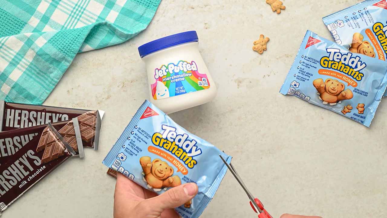 person using scissors to trim open a corner of the teddy grahams bag