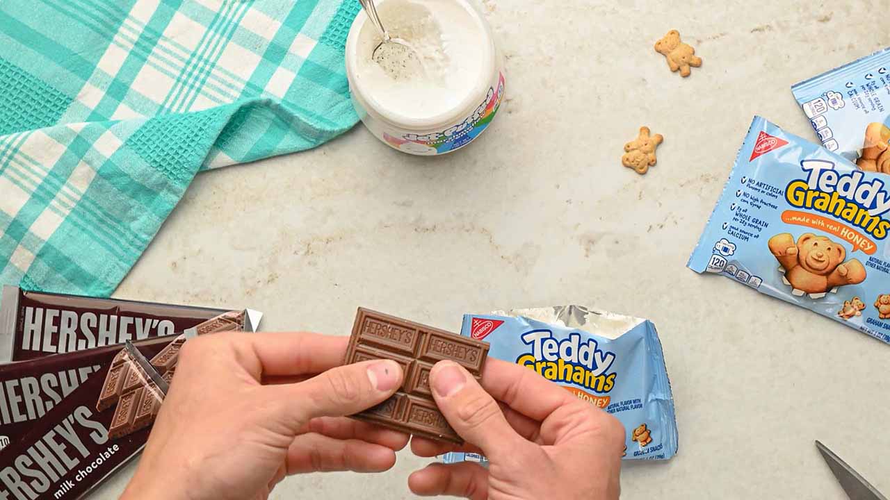 person breaking off pips from a hersheys milk chocolate candy bar