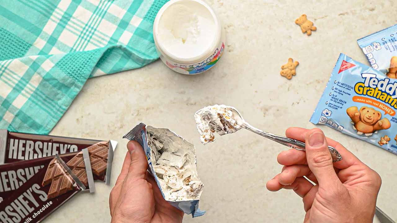 person mixing all ingredients together inside the teddy graham crackers bag