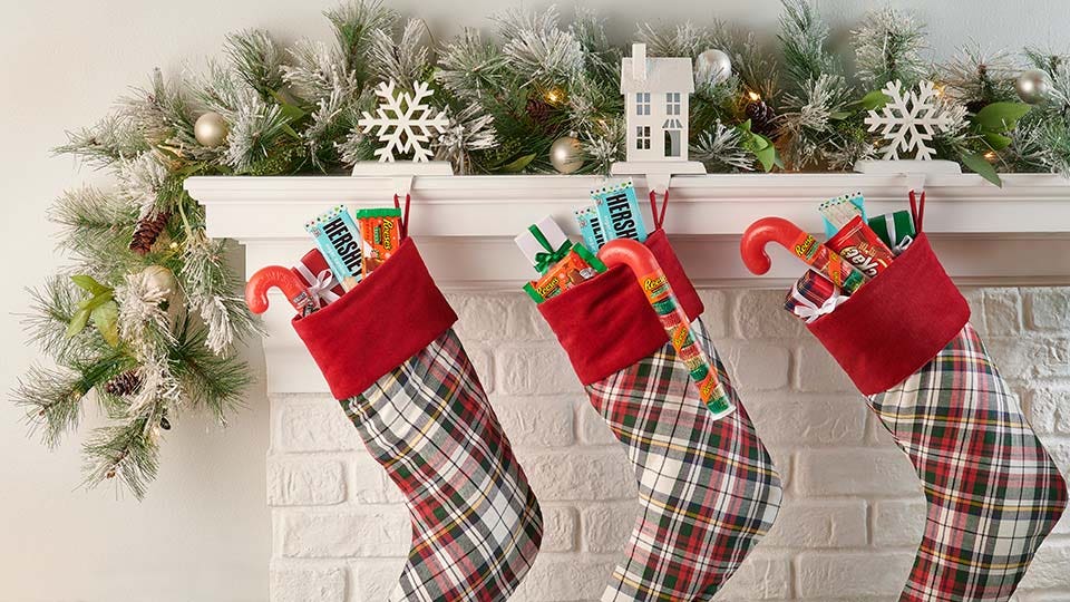 christmas stockings hanging from mantle filled with hersheys candy