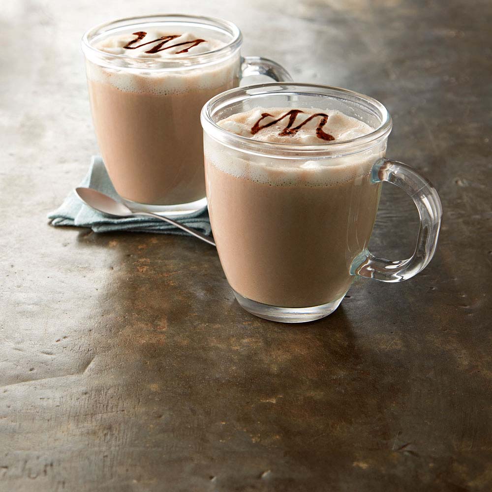 mugs of hot cocoa topped with whipped cream and chocolate drizzle