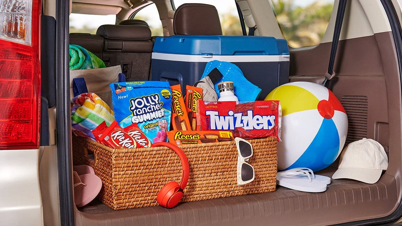 trunk of a family vehicle packed with beach picnic supplies and hershey treats