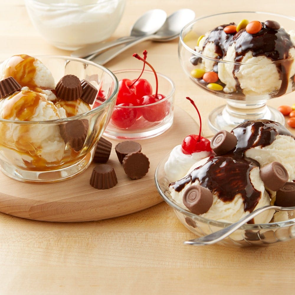 table with ice cream sundaes topped with hersheys syrups and candy