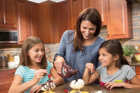 mother and daughters making ice cream sundaes using Hershey's syrup