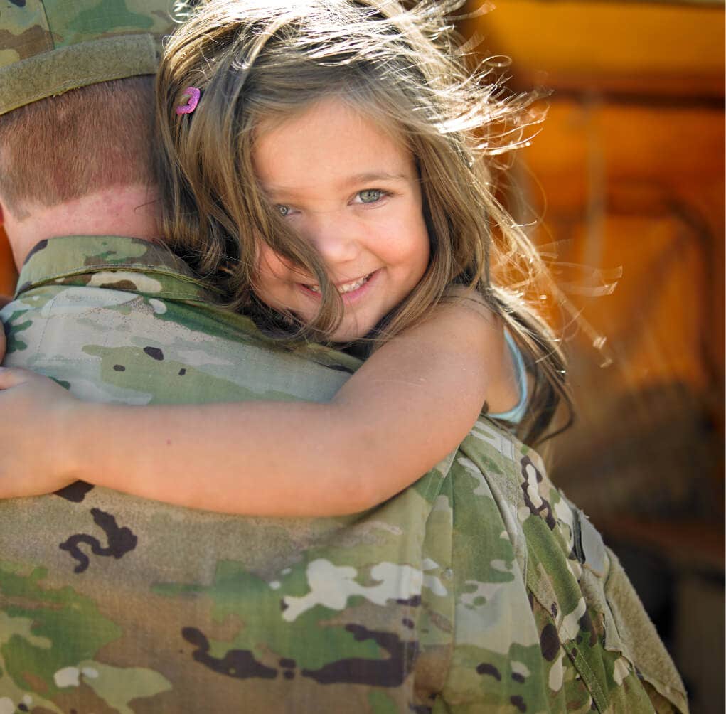 little girl being held by service member