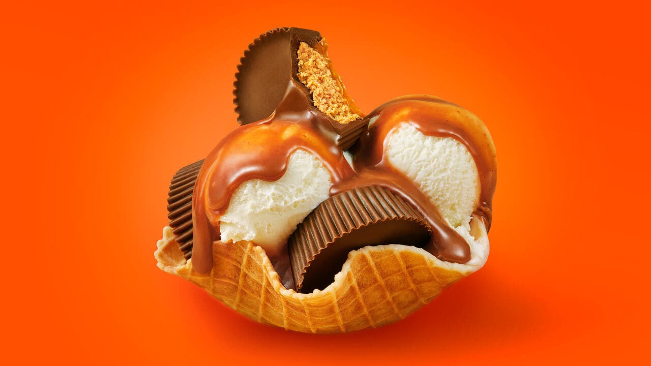 waffle cone bowl filled with ice cream topped with reeses caramel cups and caramel drizzle