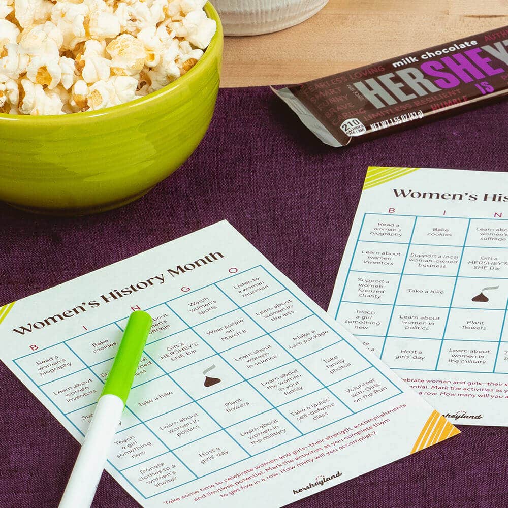 Women’s History Month bingo cards with markers, popcorn and wine.