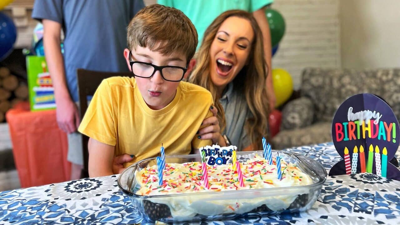 child blowing out candles on a birthday cake
