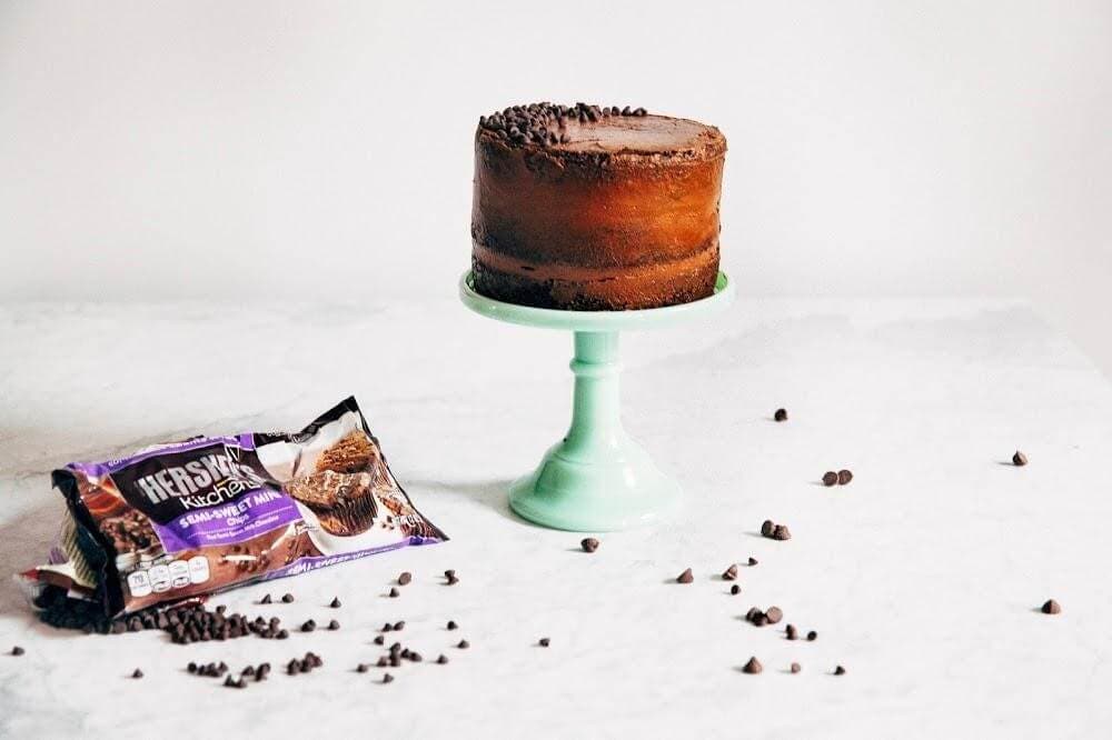 decorated cake on pedestal with chocolate chips on counter