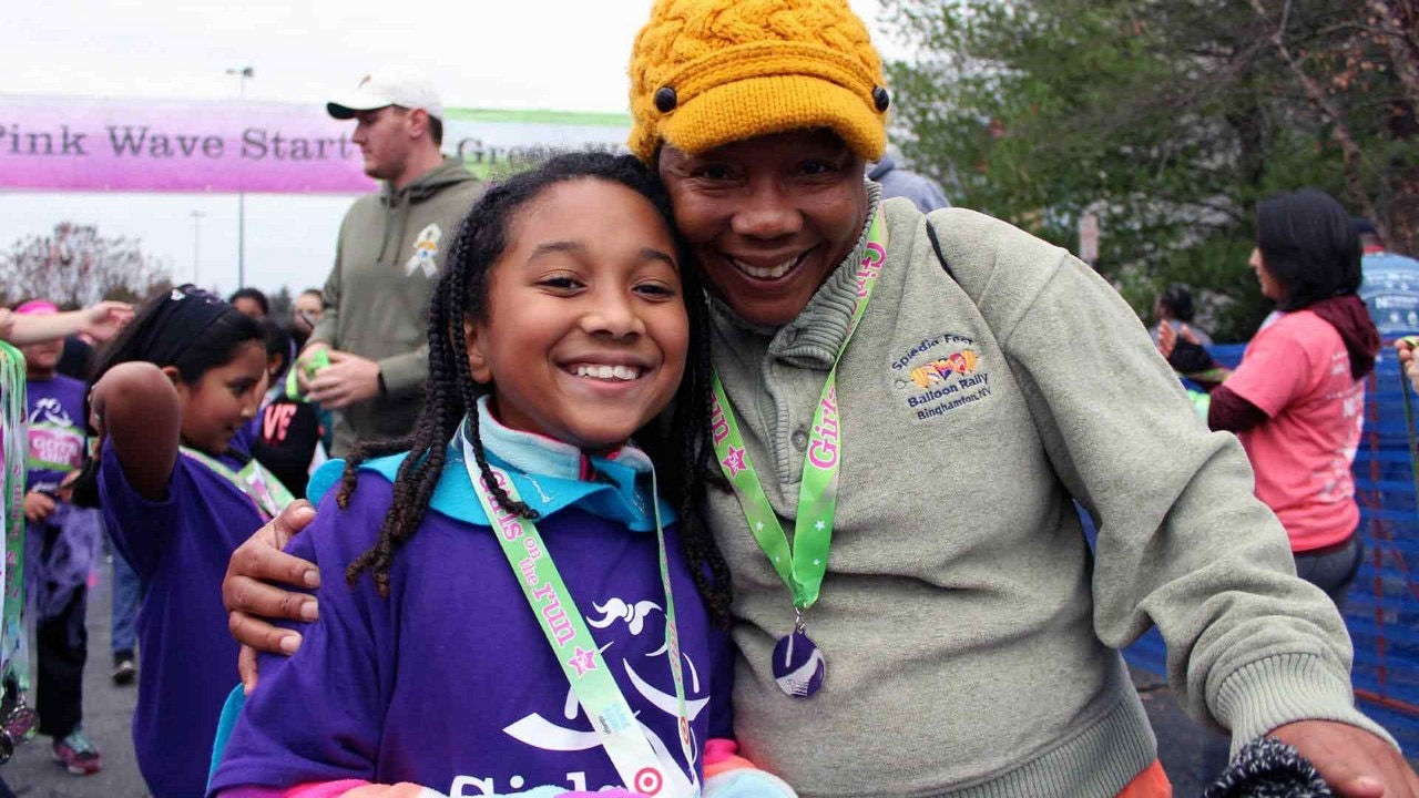 Girls on the Run community event photo featuring a girl and an adult volunteer.