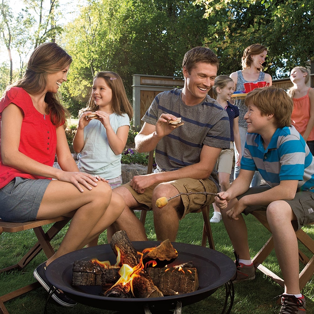 family sitting around a fire pit eating smores