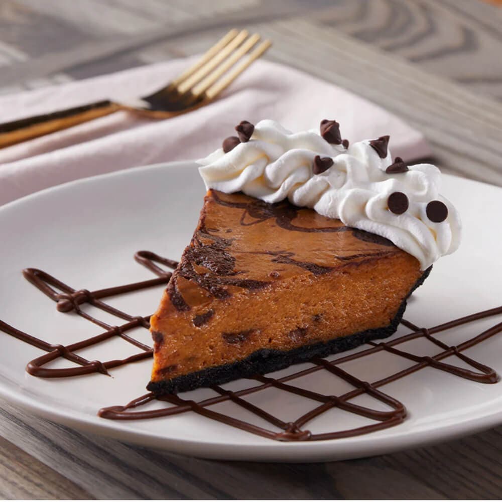 slice of pumpkin pie with chocolate swirls and topped with whipped cream