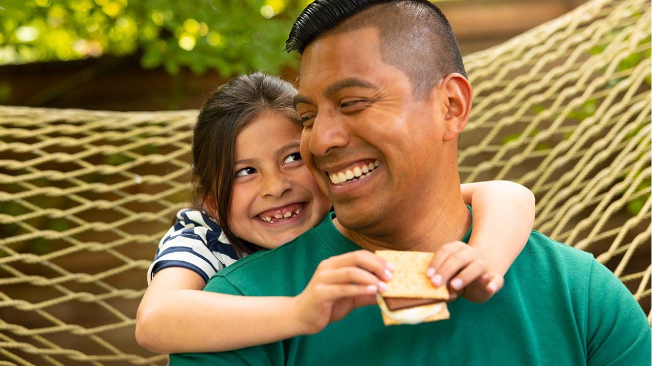 father and daughter enjoying smores outdoors