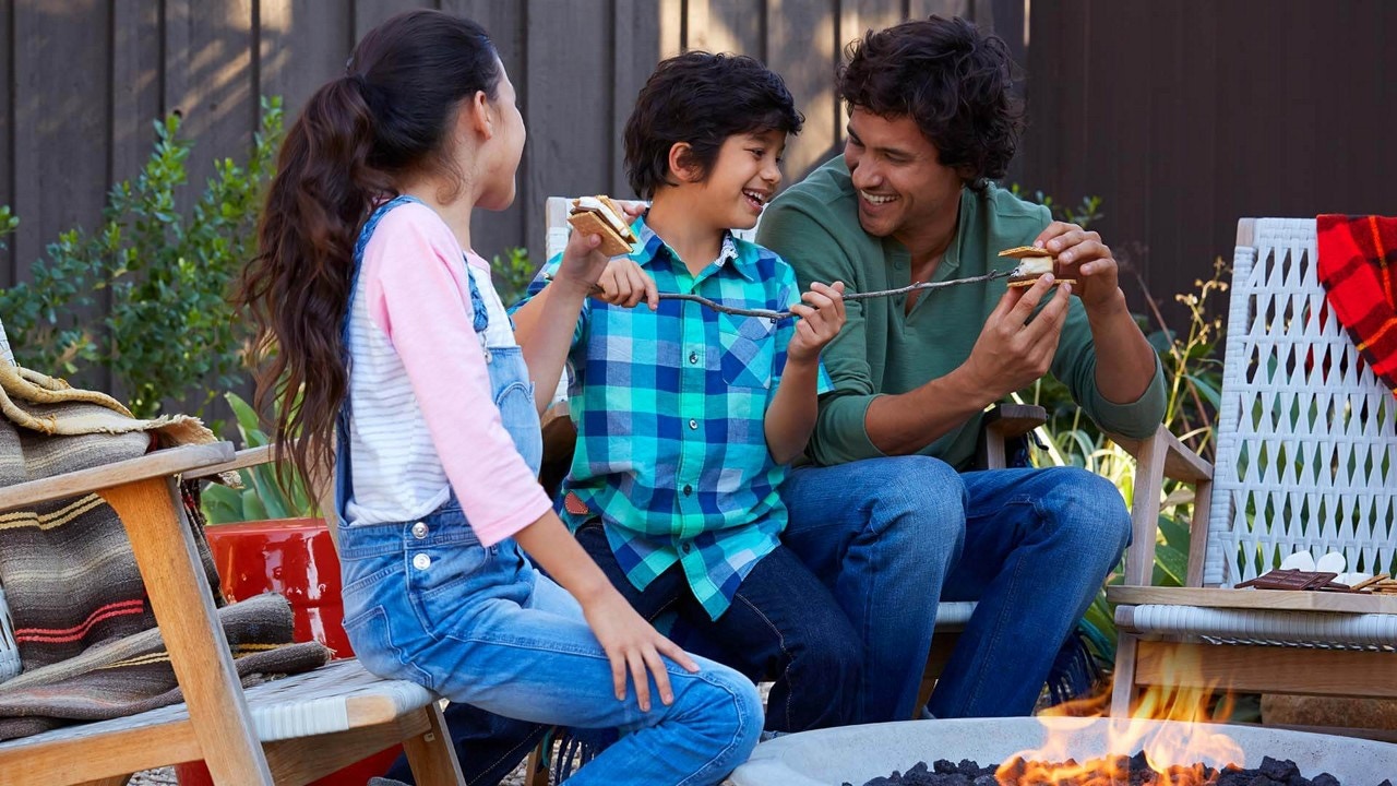  family enjoying smores outdoors around the campfire