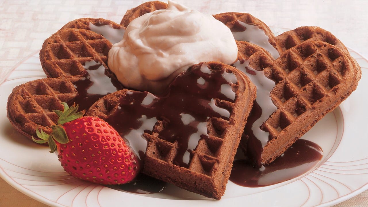 plate of chocolate heart shaped waffles with hershey's chocolate syrup on top
