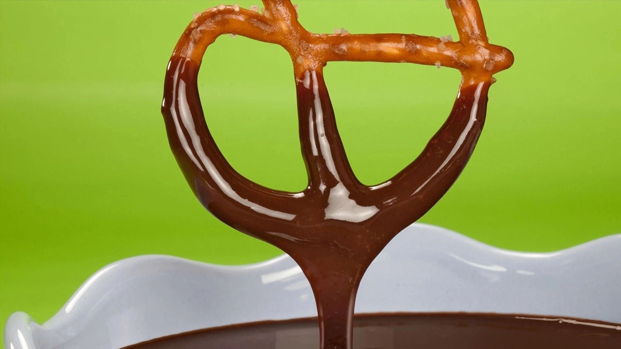 pretzel being dipped into chocolate fondue