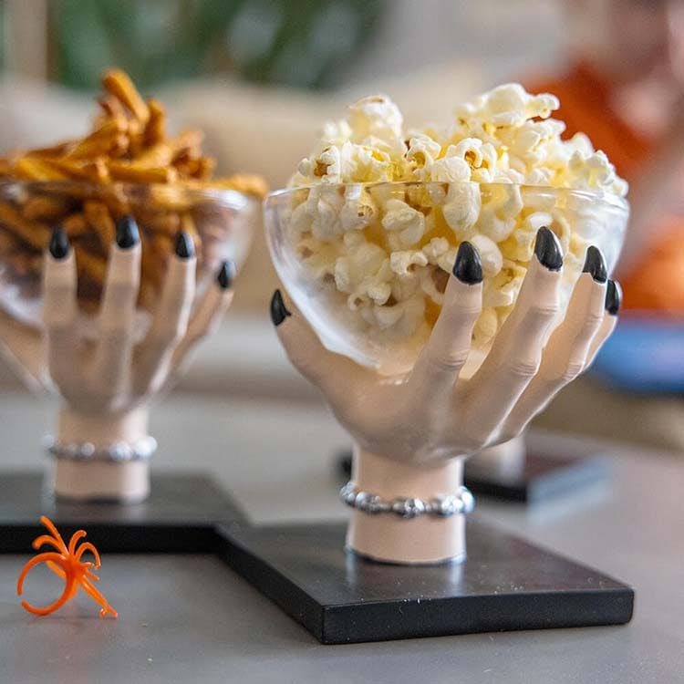 haunted hands holding bowls of assorted hersheys salty snacks