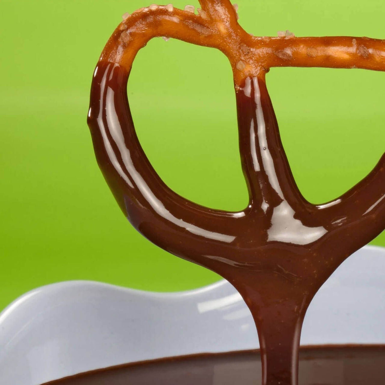 pretzel being dipped in melted chocolate