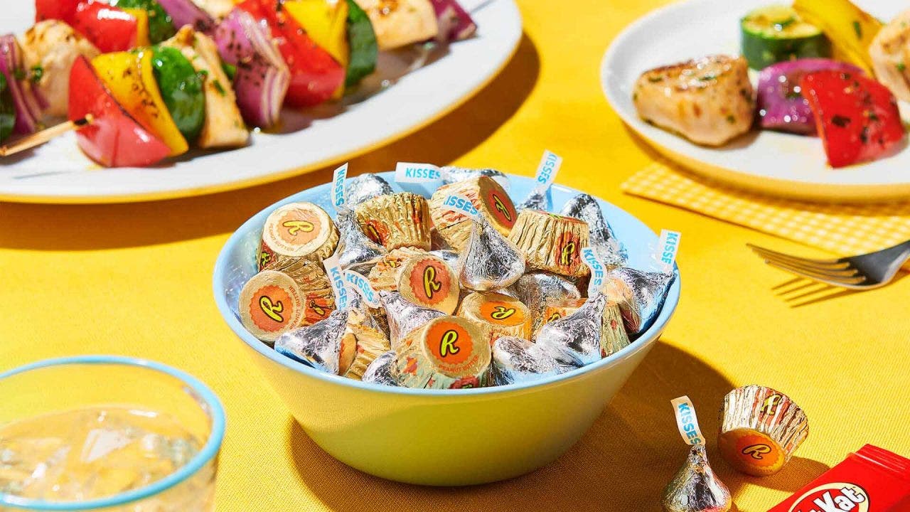 bowl filled with hersheys candy surrounded by plates of grilled food
