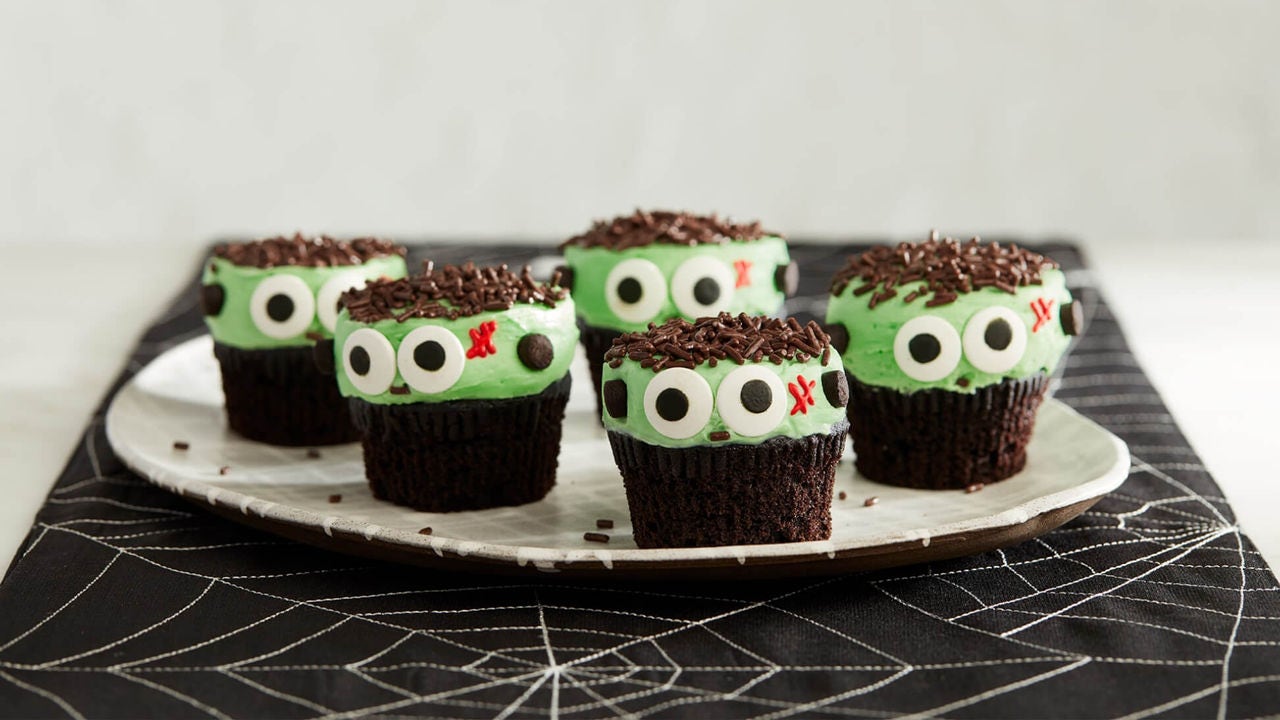 plated chocolate cupcakes decorated to look like green monsters