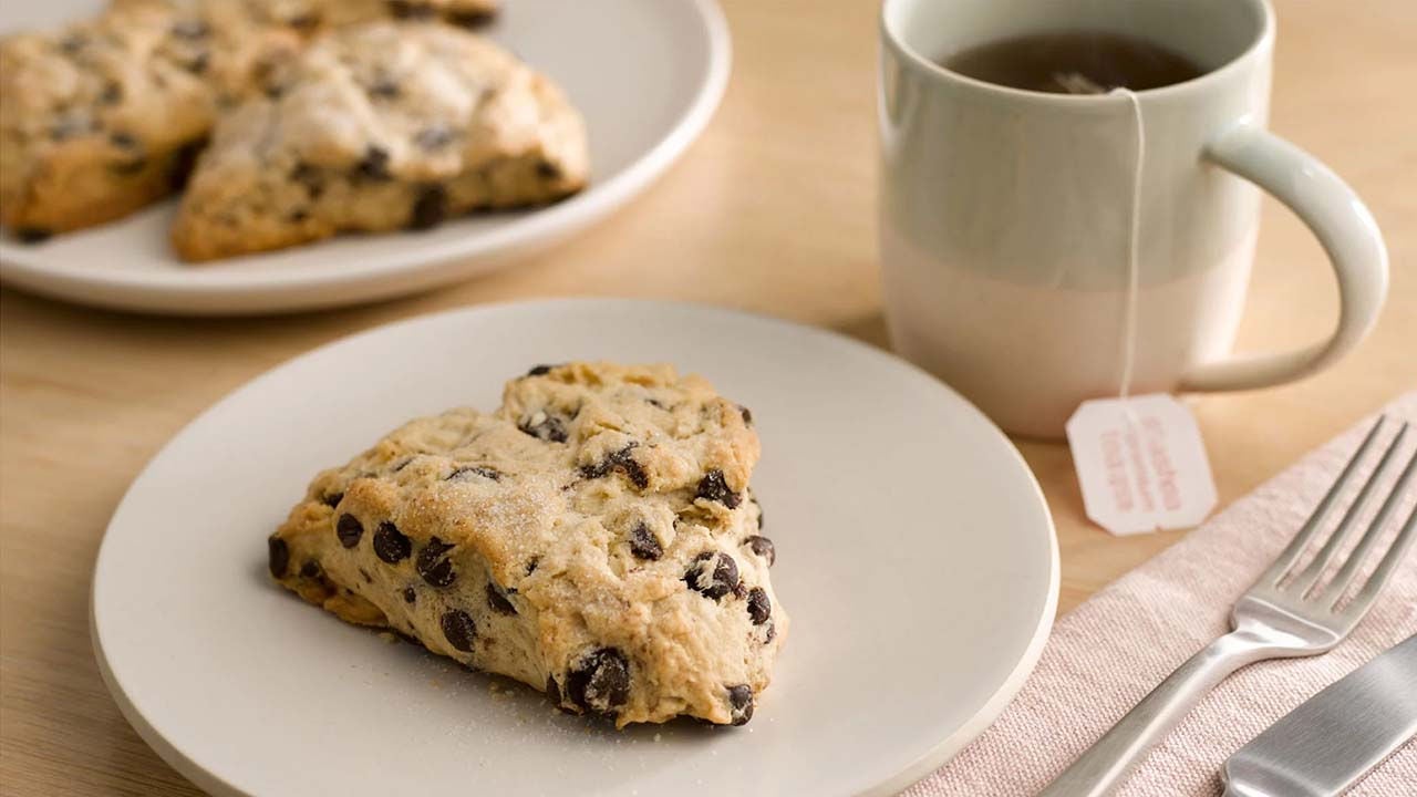 plated hersheys dark chocolate chip scone beside cup of tea