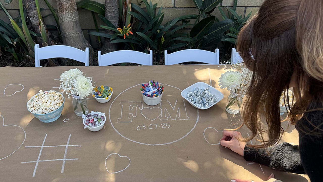 person drawing hearts on a brown paper table cover using crayons